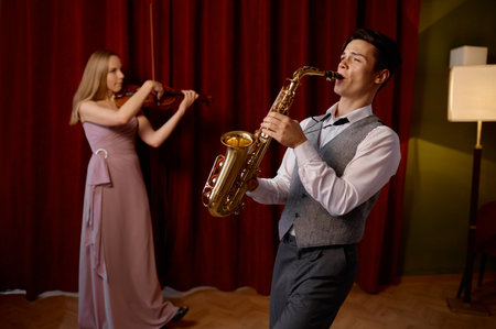 Sax man and woman fiddler duet playing classical melodyの写真素材