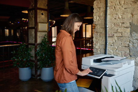 Young woman employee working on printer at coworking office