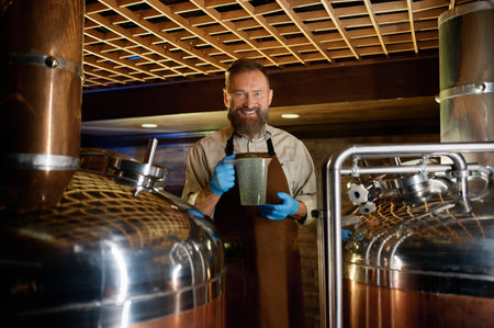 Smiling mature brewer holding plastic glass with granulated malt