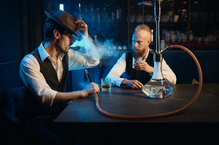 Stylish gangsters smoking hookah in bar having business meetingの写真素材