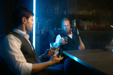Two young stylish man relax and smoking hookah in bar