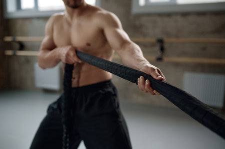 Young strong man pulling training sports rope front viewの写真素材