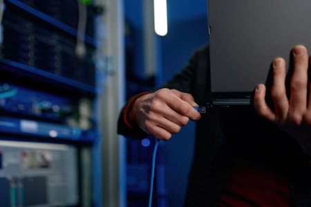 IT technician switching wire to laptop computer closeupの写真素材