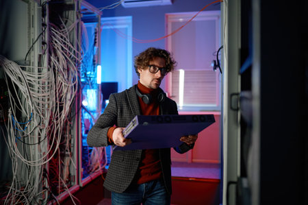 Portrait of it specialist holding hardware in hand standing in server room