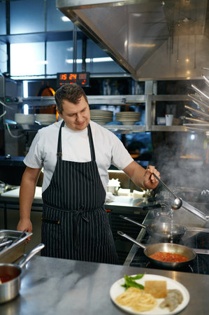 Chef adding white wine to frying pan with tomato sauce for pastaの写真素材