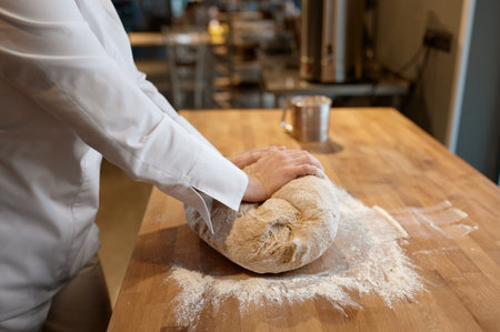 Baking process, closeup baker hands kneading dough on tableの写真素材