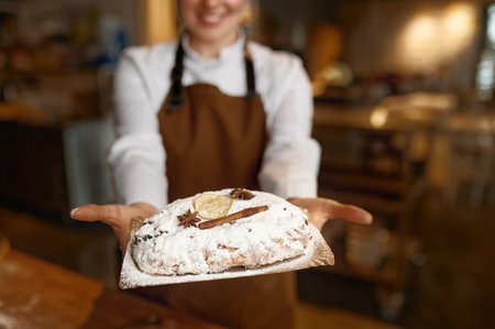 Young woman baker wearing uniform showing fresh bread closeupの写真素材
