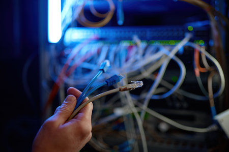 Cropped closeup shot of hand connecting cables to network server