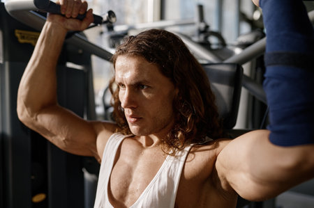 Closeup view on face of serious concentrated sportsman training on gym equipment