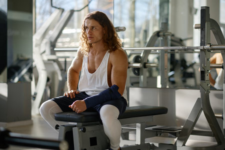Portrait of tired sportsman sitting on fitness box while rest after training