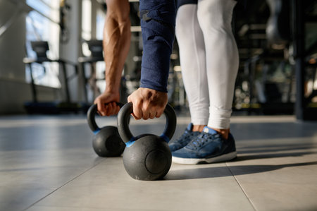 Cropped closeup shot of sportsman hands taking kettlebell from floorの写真素材
