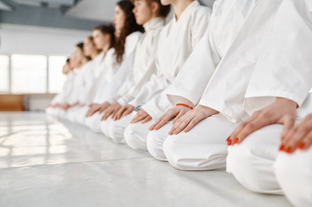 Young woman team in white martial arts uniform sitting on floor in gymの写真素材
