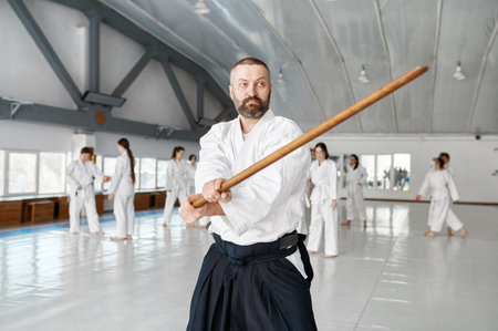 Portrait of aikido sensei master with wooden sword at group training