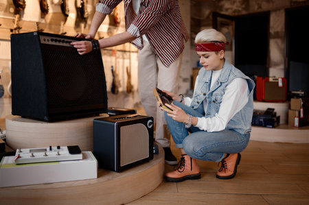 Man and woman musicians buying amplifier at professional music shop