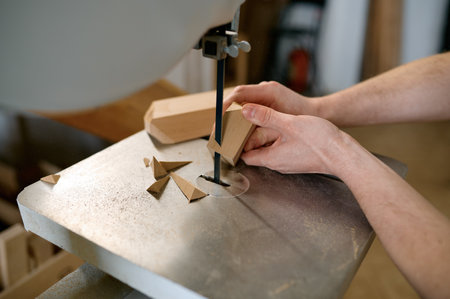 Carpenter using band saw to cut plywood, closeup shot with selective focusの写真素材