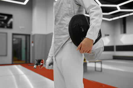 Crop view of fencer standing over gym interior