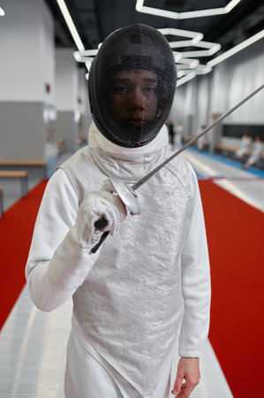 Portrait of teenage boy fencer wearing uniform posing with swordの写真素材