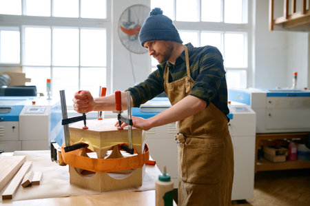 Young male jointer fixing wooden construction or assembling of furniture