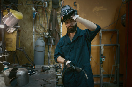 Portrait of repairman taking off protective helmet after hard work with welderの写真素材
