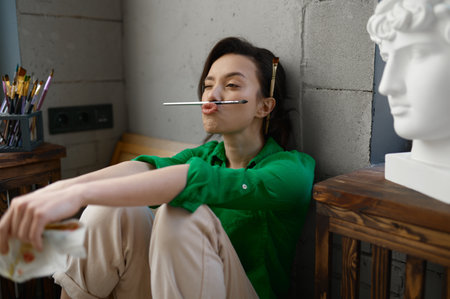 Carefree funky woman artist fooling around with paintbrush enjoying relaxの写真素材