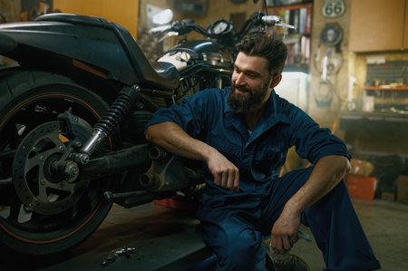 Satisfied smiling mechanic feeling glad looking at repaired motorcycleの写真素材