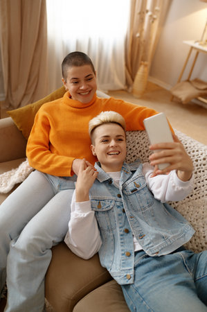 Happy smiling lgbt woman couple holding online video chat with friends on phone