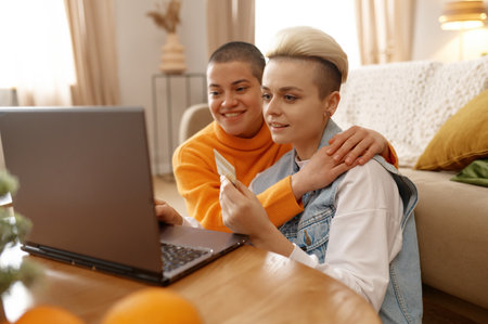 Happy lgbt woman doing online payment using laptop and credit cardの写真素材