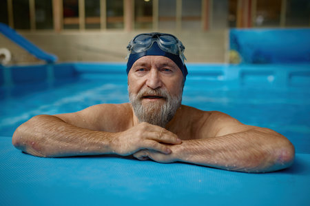 Portrait of mature senior man wearing swimming hat and goggles at poolの写真素材