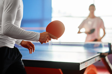 Selective focus on two sportive people playing table tennis indoorsの写真素材