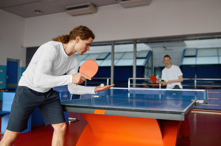 Man and woman playing table tennis, focus on sportsman player servingの写真素材
