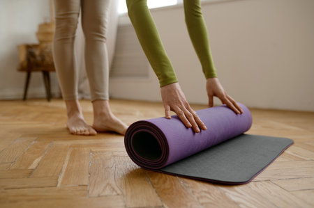 Closeup woman rolling yoga mat on wooden floorの写真素材