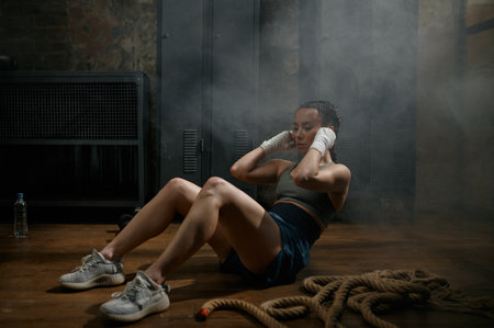Attractive woman boxer doing abs crunch workout during training at gym