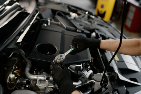 Closeup male mechanic hands with wrench working under opened car hood