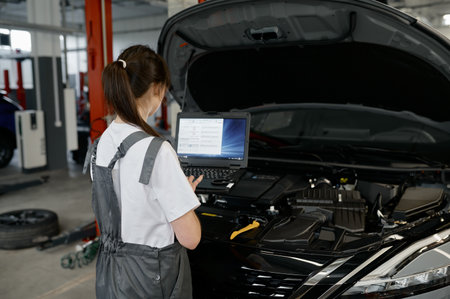 Back view on woman auto engineer doing computer diagnostic