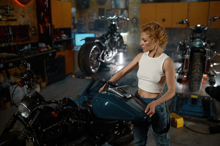 Attentive female master repairing bike at garage workshopの写真素材