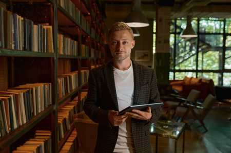 Portrait of successful male office worker standing with mobile tablet