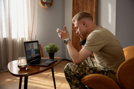 Nervous veteran talking loudly to psychiatrist during videoconferencingの写真素材