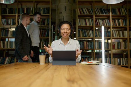 Female office worker wearing headphones working on laptop computer