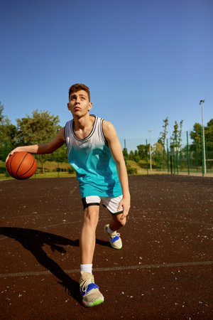 Young teenager training on street court playing basketballの写真素材