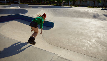Active young woman on roller skates enjoying freestyle riding on rollerdrom
