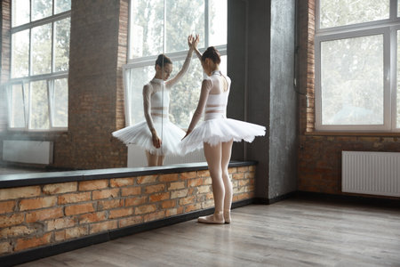 Worried ballerina standing near huge mirror at dance studioの写真素材