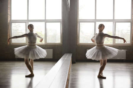 Beautiful young ballerina training classic ballet in studio with huge mirrorの写真素材