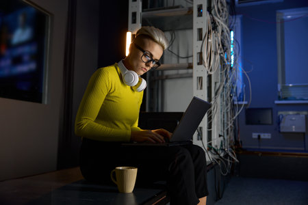 Young woman working with laptop in server room