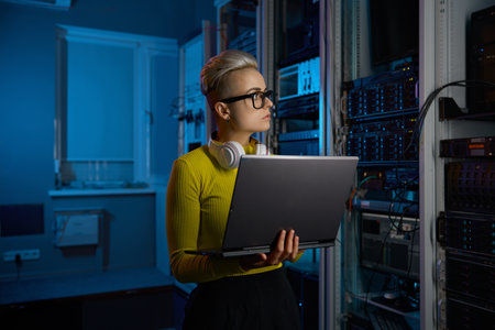 Portrait of concentrated woman coder solving problem in data centerの写真素材