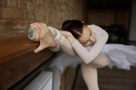 Flexible girl ballerina doing stretching exercise at dance studioの写真素材