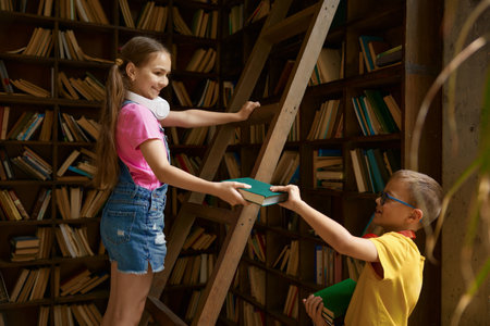 Children being on duty putting away books in home or school libraryの写真素材