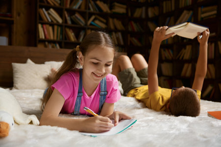 Little sister and brother doing homework lying in bed