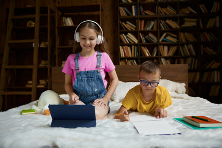 Happy schoolkid studying and preparing homework together at homeの写真素材