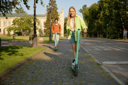 Interracial company of students using electric scooter vehiclesの写真素材