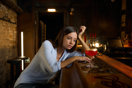 Lonely sad woman sitting at bar with glass of wineの写真素材